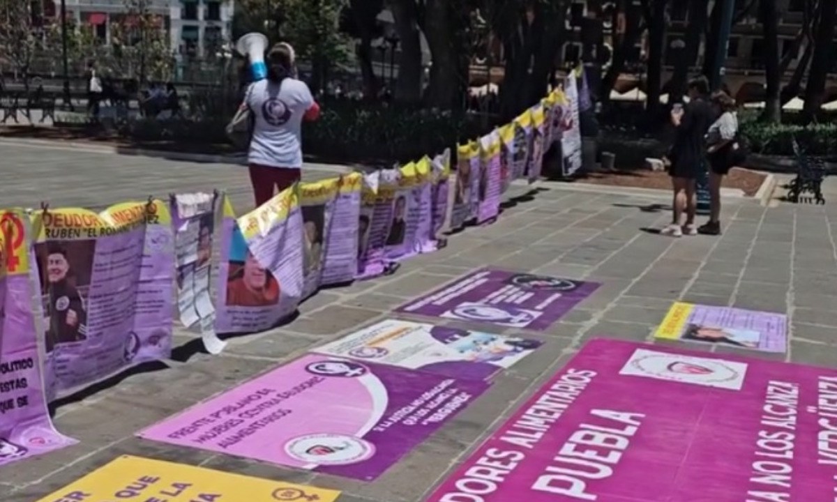 El Frente Poblano de Mujeres contra Deudores Alimentarios instaló un “tendedero” en el zócalo de la capital, con el objetivo de exhibir las fotografías de decenas de hombres que han incumplido durante meses o años en sus obligaciones económicas con sus hijos | FOTO: Especial